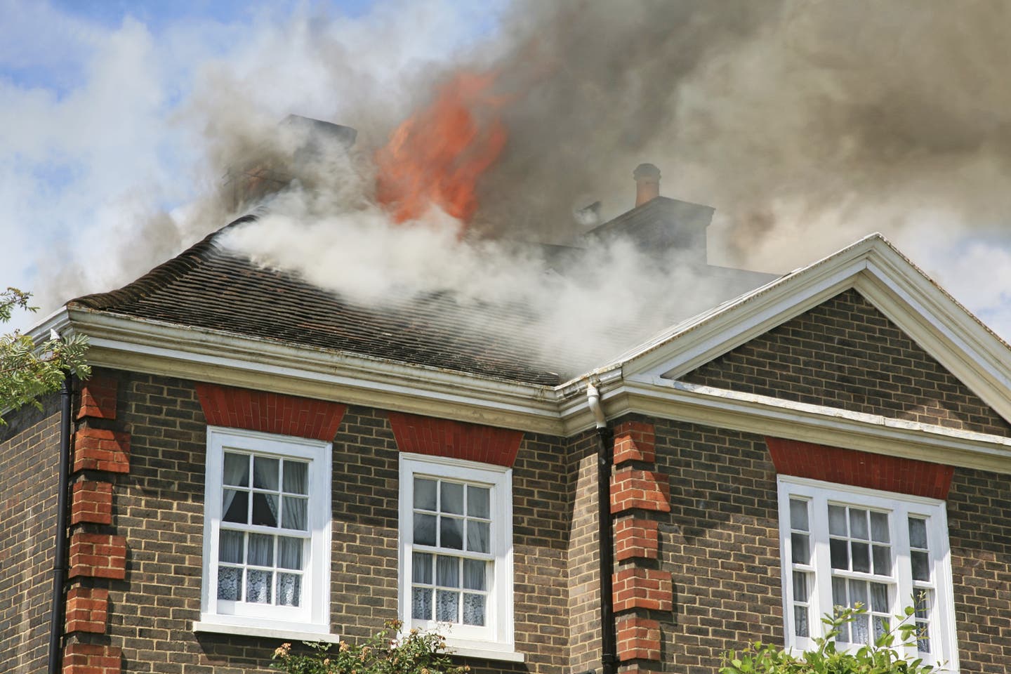 Fire breaking through the roof of a house. It's important to know what to do after a house fire.